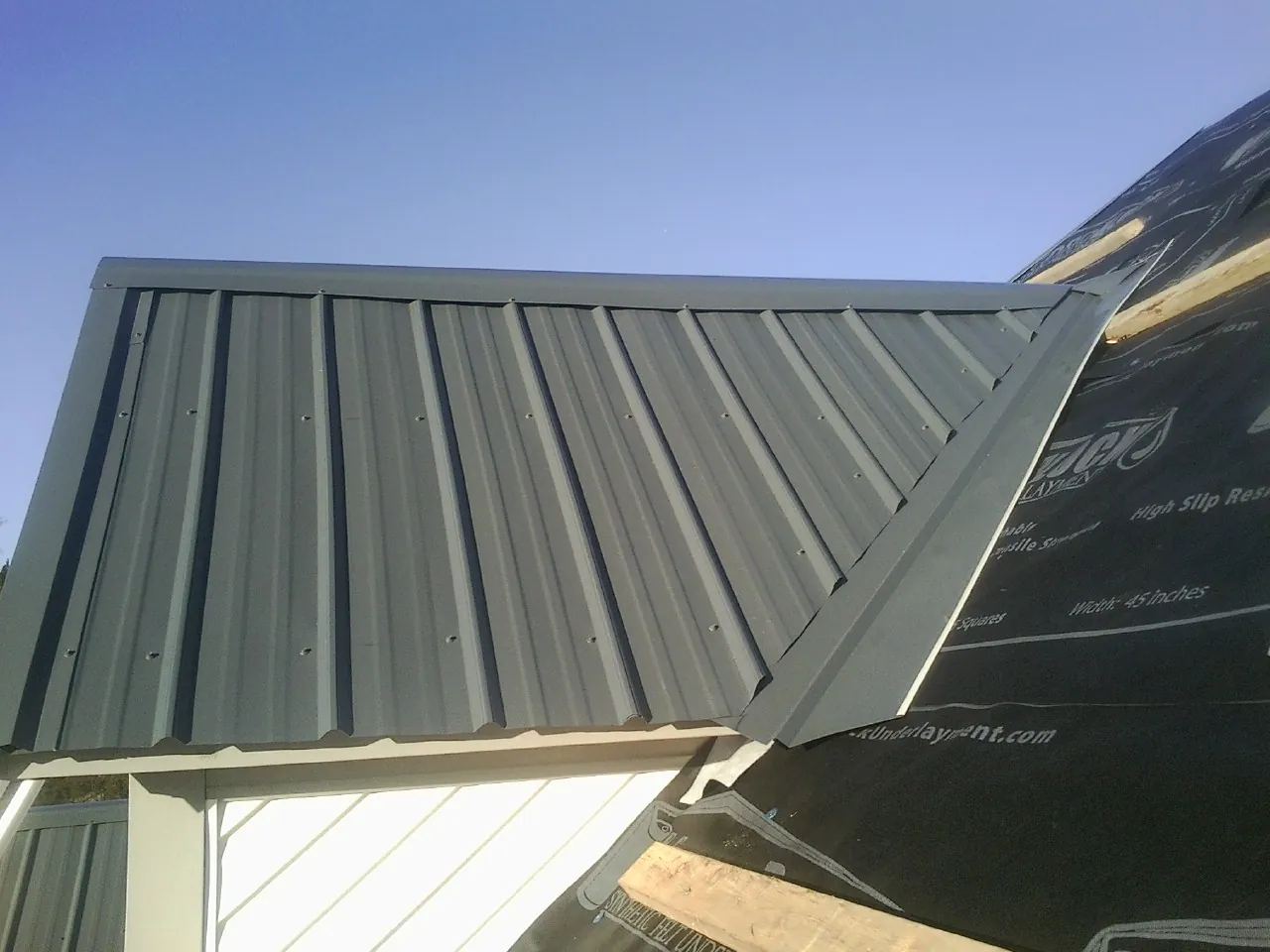 Gray metal roof panels going on over a garage gable in Ashland