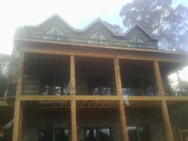 Dormers and porch framing on a large log home under construction — Roof Coating work by our crew in Ashland